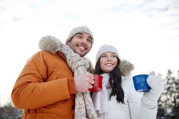 happy couple with tea cups over winter landscape