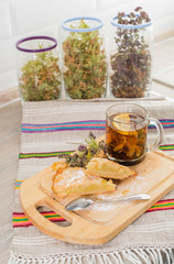 Hot cup of bio herbal tea and a piece of lemon pie on a wooden b