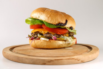 Tasty cheese beef burger with lettuce, cheddar, barbecue sauce, tomatoes, pickles and tzatziki