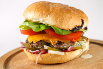 Tasty cheese beef burger with lettuce, cheddar, barbecue sauce, tomatoes, pickles and tzatziki