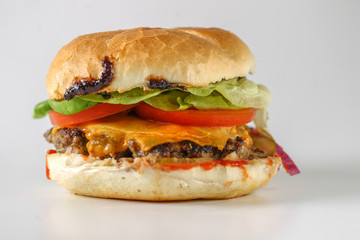 Tasty cheese beef burger with lettuce, cheddar, barbecue sauce, tomatoes, pickles and tzatziki