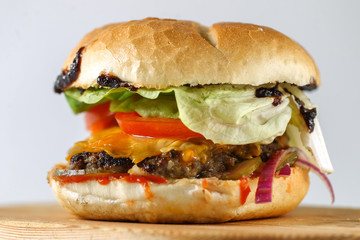 Tasty cheese beef burger with lettuce, cheddar, barbecue sauce, tomatoes, pickles and tzatziki