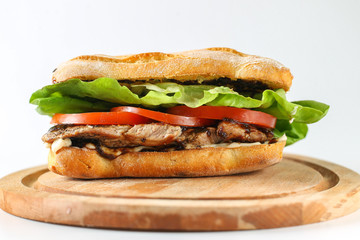 Tasty pork steak sandwich in a ciabatta with tomatos, lettuce, mayonnaise and barbecue sauce
