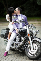 Fototapeta na wymiar Handsome groom and beautiful bride on retro black motorcycle in