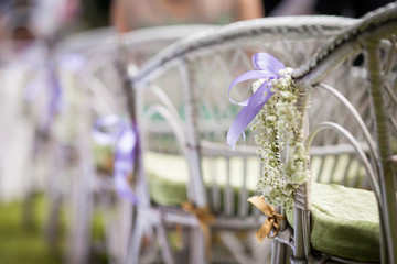 Beautiful white chairs at wedding aisle with flowers and a ribbo