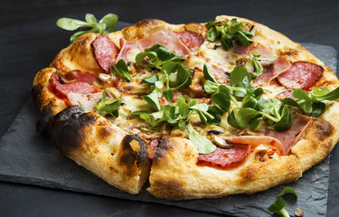 Pizza salami,cheese and ham with cornsalad leaves