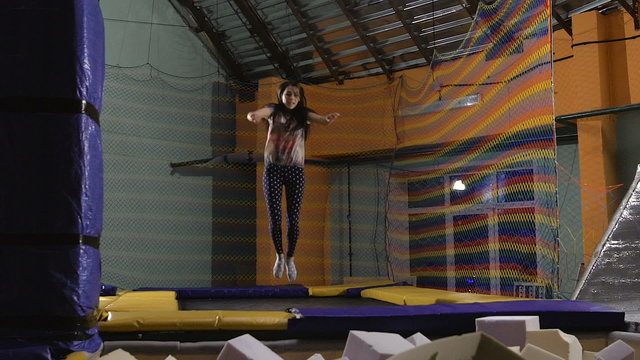 A young woman in a T-shirt. Jumping on a trampoline is ridiculous. 
