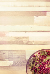Salad with pomegranate grains on the wooden background.
