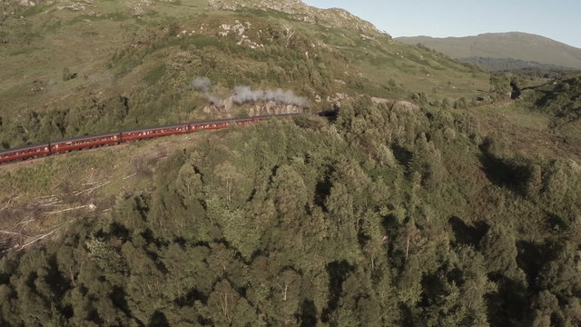 Aerial shot of the Jacobite Steam Train going through stunning scenery in the Scottish highlands 