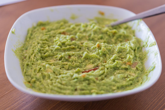 Aerial view closeup of homemade spicy guacamole dip served in bo