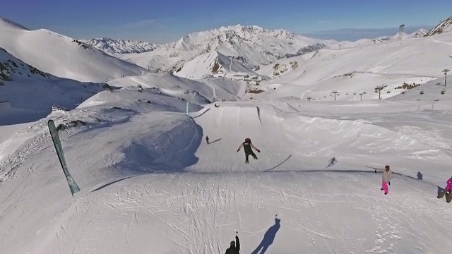 Aerial of a snowboarder jumping in the snowpark. This is a slowmotion video.