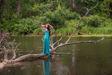 girl wearing dress standing in river near forest