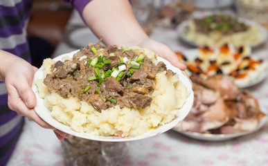 potatoes with meat in a plate in his hands