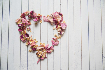 Vintage heart made of dried petals on wooden white background