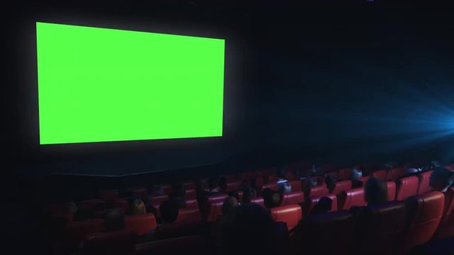 Group of people are watching a green screen mock-up film screening in a movie cinema theater. Shot on RED Cinema Camera.