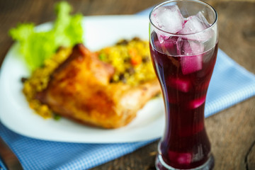 Dishes from chicken thigh with rice and lettuce and a glass of j