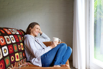 Smiling older woman relaxing at home with cup of tea
