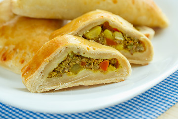 Tasty cake stuffed with meat on a white plate and blue checkered