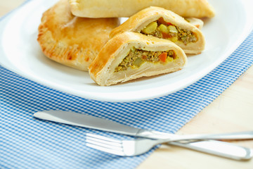 Tasty cake stuffed with meat on a white plate and blue checkered