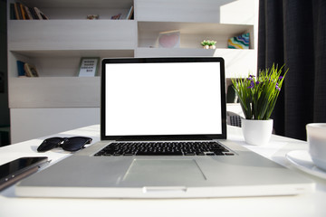 Office desk next to a window with laptop and tablet pc 