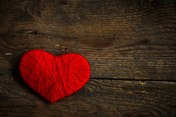 Naklejka na ściany i meble Red heart shape made from wool on old shabby wooden background