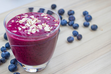 Healthy blueberry-banana smoothie on wooden table with fresh fruits.