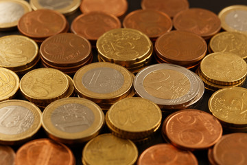Layer of euro coins on a black background