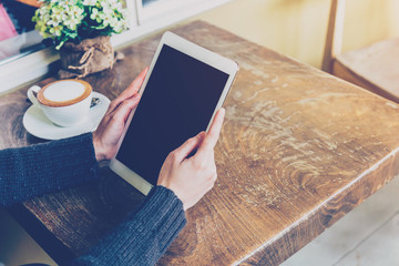 Woman using tablet in coffee shop with vintage tone.