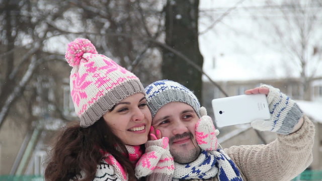 Loving couple in winter outdoors making selfie on smartphone