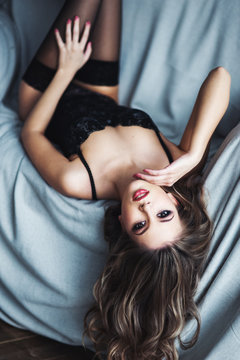 Young woman in black lingerie lying in sofa
