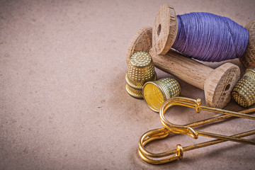 Spools of sewing threads thimbles clasp pins on vintage backgrou