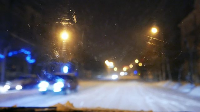 Urban traffic in blizzard, snowfall. Snowflakes and rain drops on the windshield