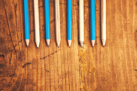 Blue and brown lined up pencils on rustic wooden table