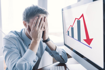 Frustrated stressed shocked business man with financial market chart graphic going down on grey...