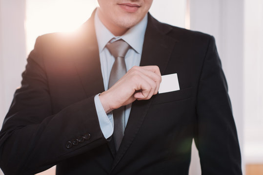 businessman in a black suit and gray tie place or take out credit card in pocket