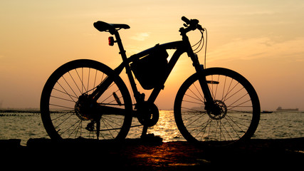 Fototapeta na wymiar Silhouette of mountain bike at sea with sunset sky