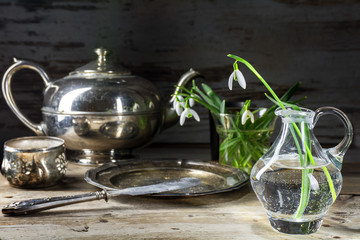 morning with snowdrops and silver breakfast dishes on a rustic w