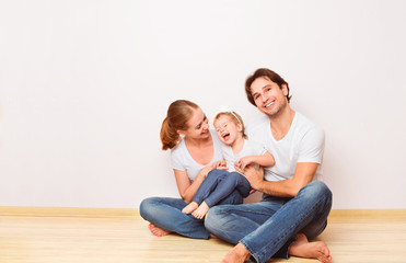 Happy family on  floor near  empty  wall in the apartment bought