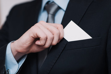 businessman in a black suit and gray tie place or take out credit card in pocket