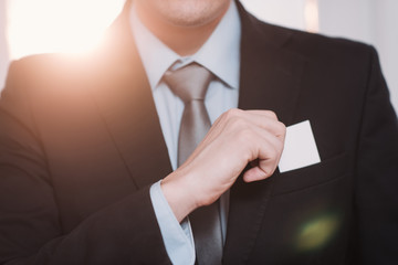 businessman in a black suit and gray tie place or take out credit card in pocket