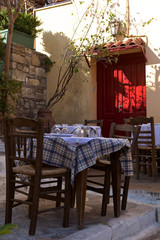 Street cafe terrace in front of a red door in Athens.