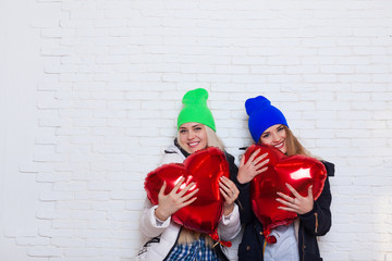 Fototapeta na wymiar Two Girls Hold Red Heart Shape Love Balloons Valentine Day