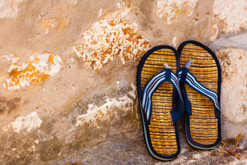 Beach flip-flops on the old wall background