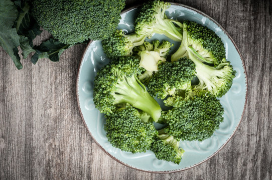 Full plate raw broccoli  rustic wooden table