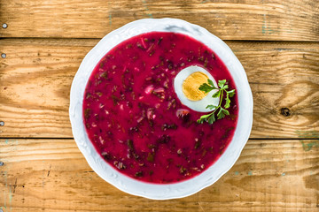 Beetroot soup with egg on background of  wooden planks