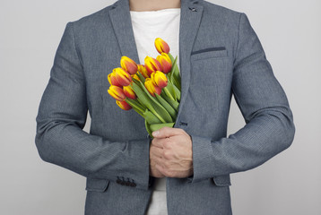Man in a jacket holding a bouquet of tulips