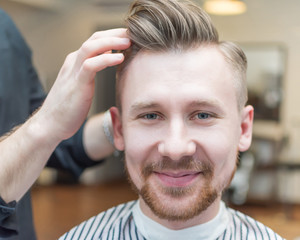 Obraz premium Portrait of happy man getting an haircut from hairdresser in barber shop