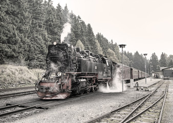 Fototapeta na wymiar historic German black steam powered railway train at Schierke station, Schierke, Harz, Germany, Europe, vintage filtered style 
