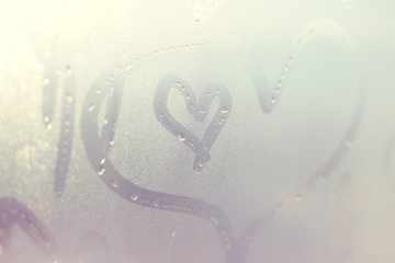 Closeup on drawing heart on wet window