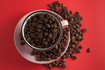 Cup of coffee beans on a red background